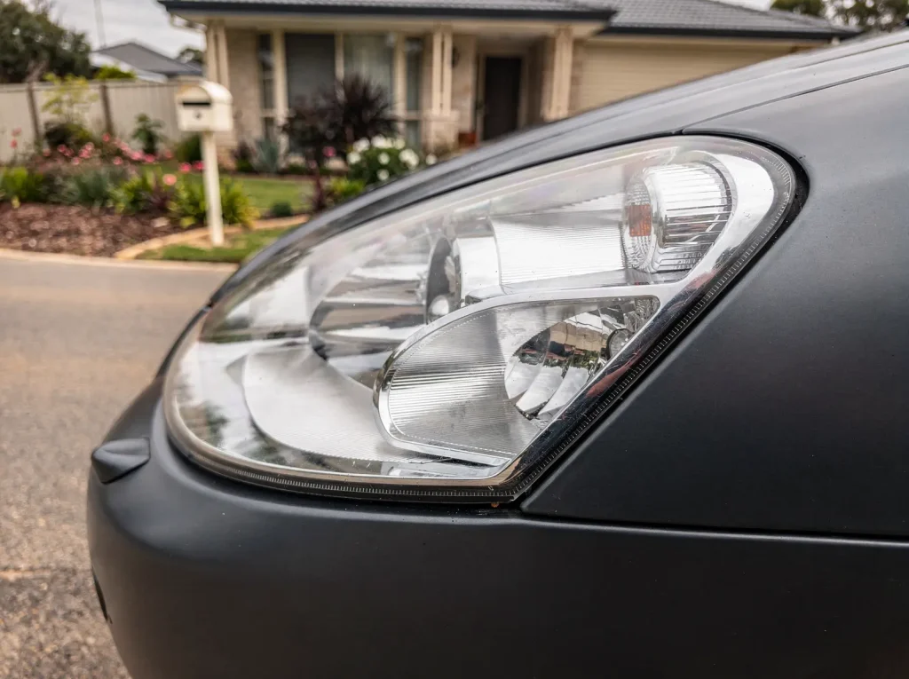 Restored crystal-clear headlight lens with sharp chrome reflectors after Perth car detailing.