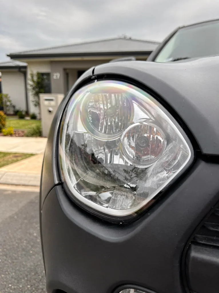 Restored crystal-clear headlight lens with sharp chrome reflectors after Perth car detailing.